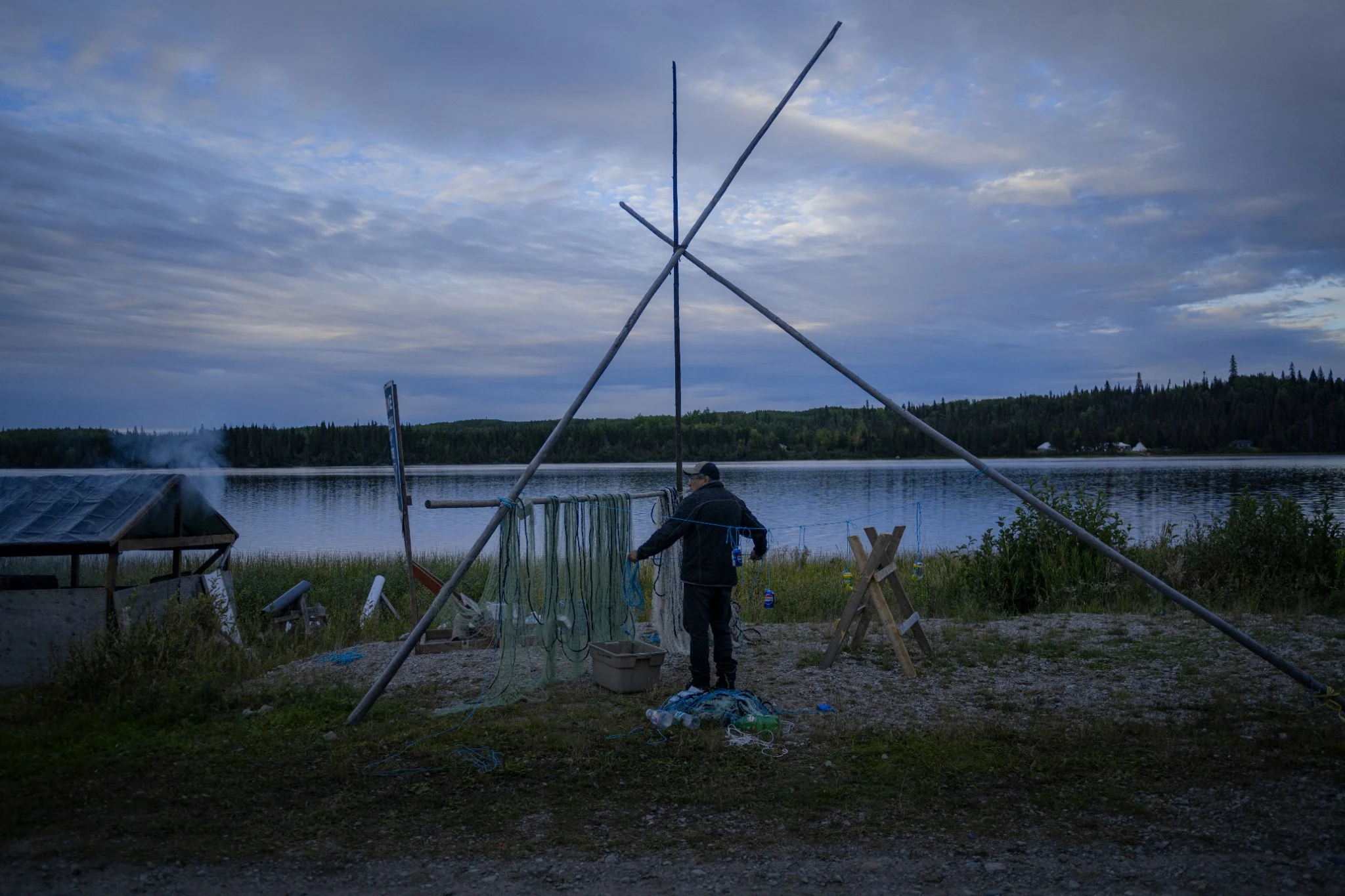Hanging a fishing net beside a lake at dusk