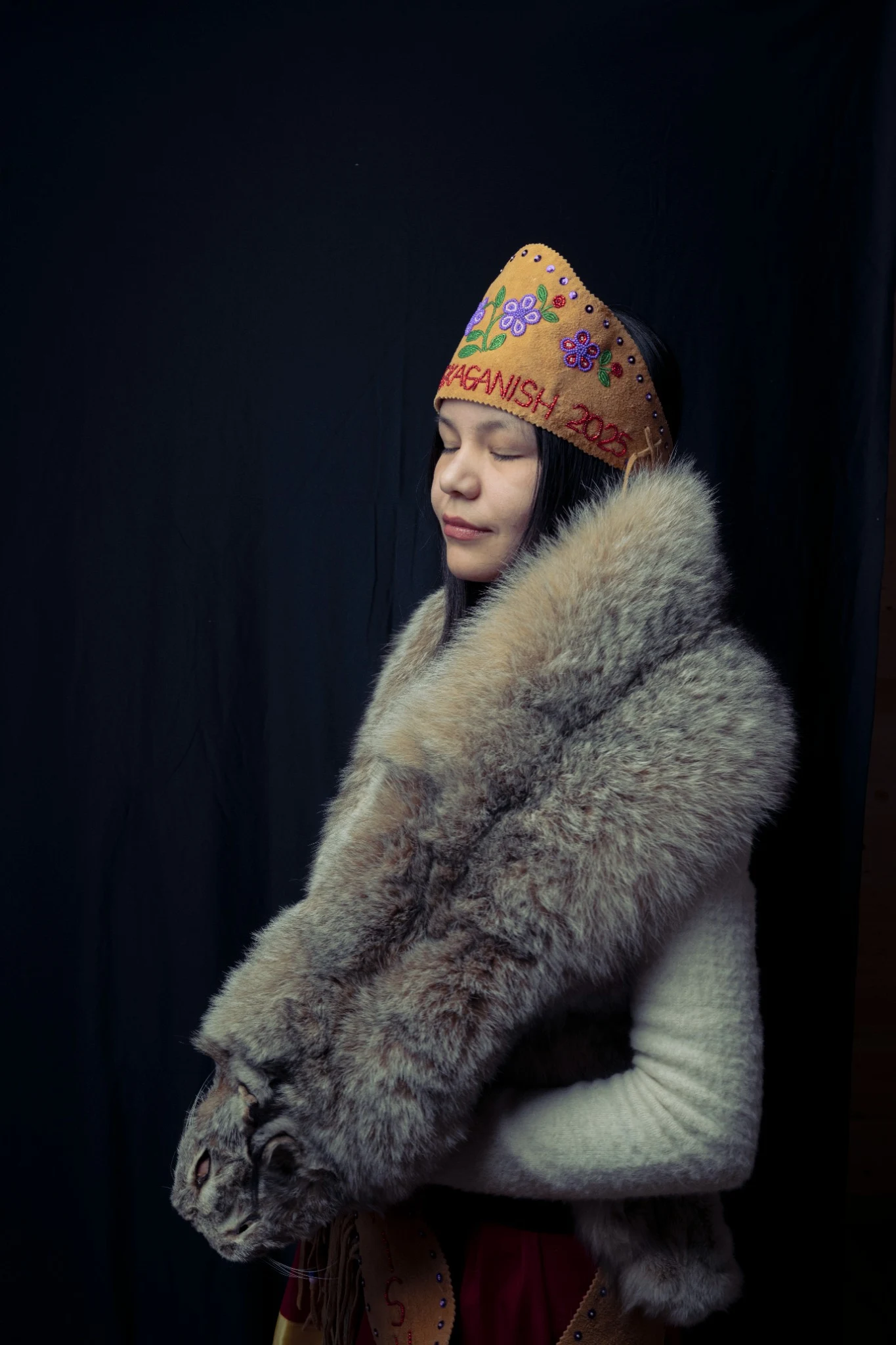 Portrait holding a lynx pelt against a dark background