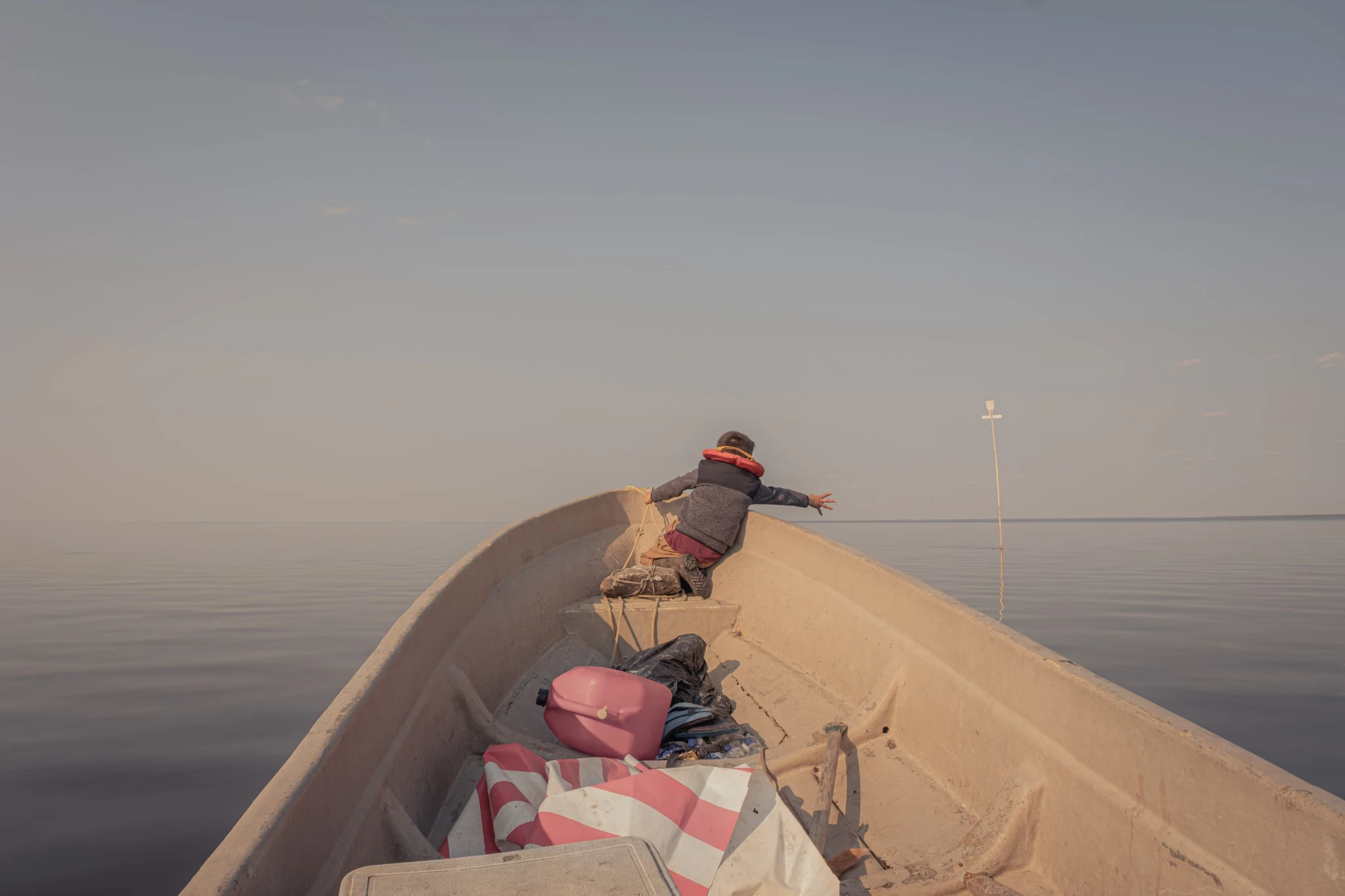 Child reaching out from the bow of a canoe