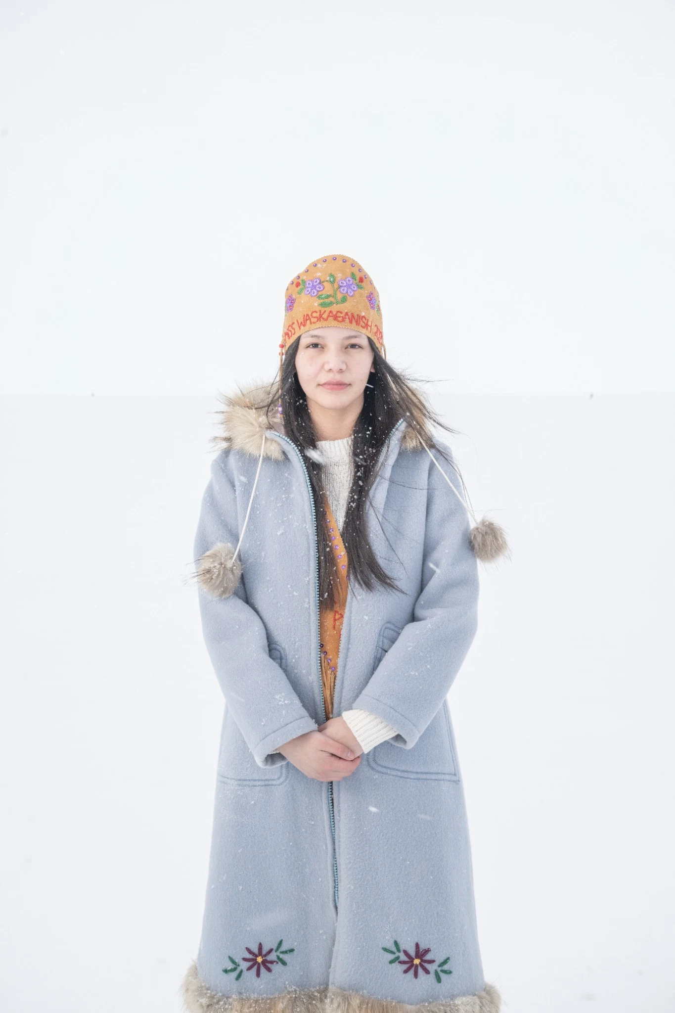 Portrait in a pale blue coat and beaded hat in falling snow