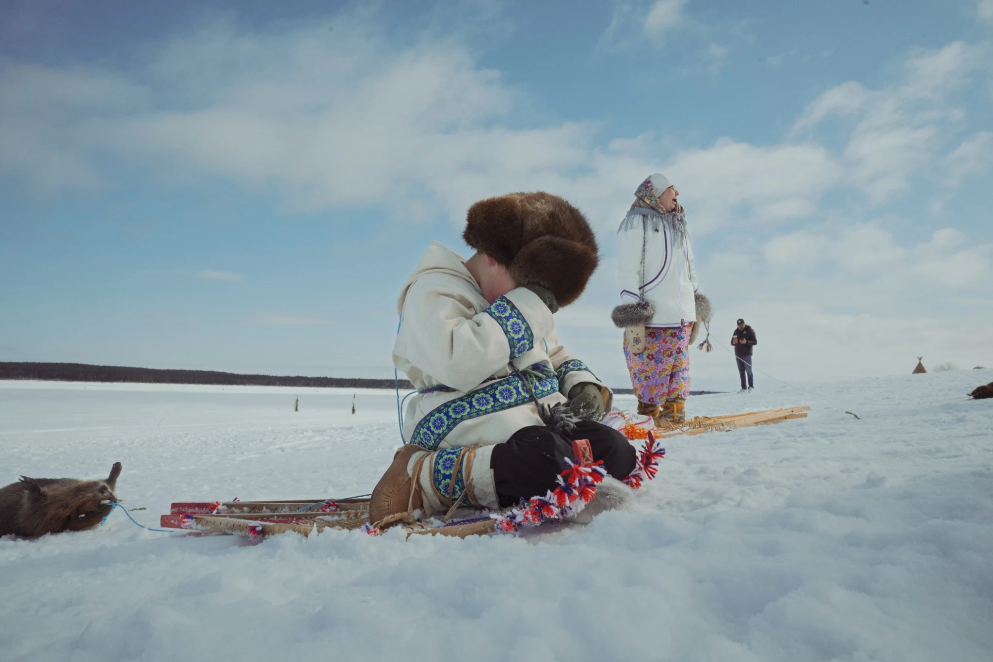 Child resting on snowshoes on a frozen lake