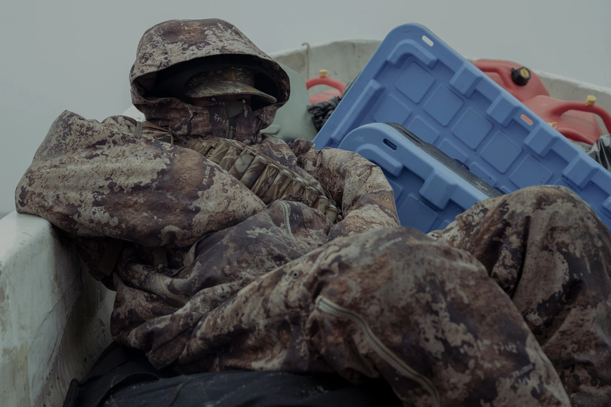 Traveller in camouflage among supplies in a boat