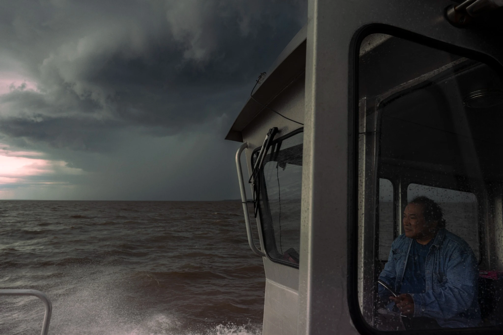 Woman steering a boat beneath a stormy sky