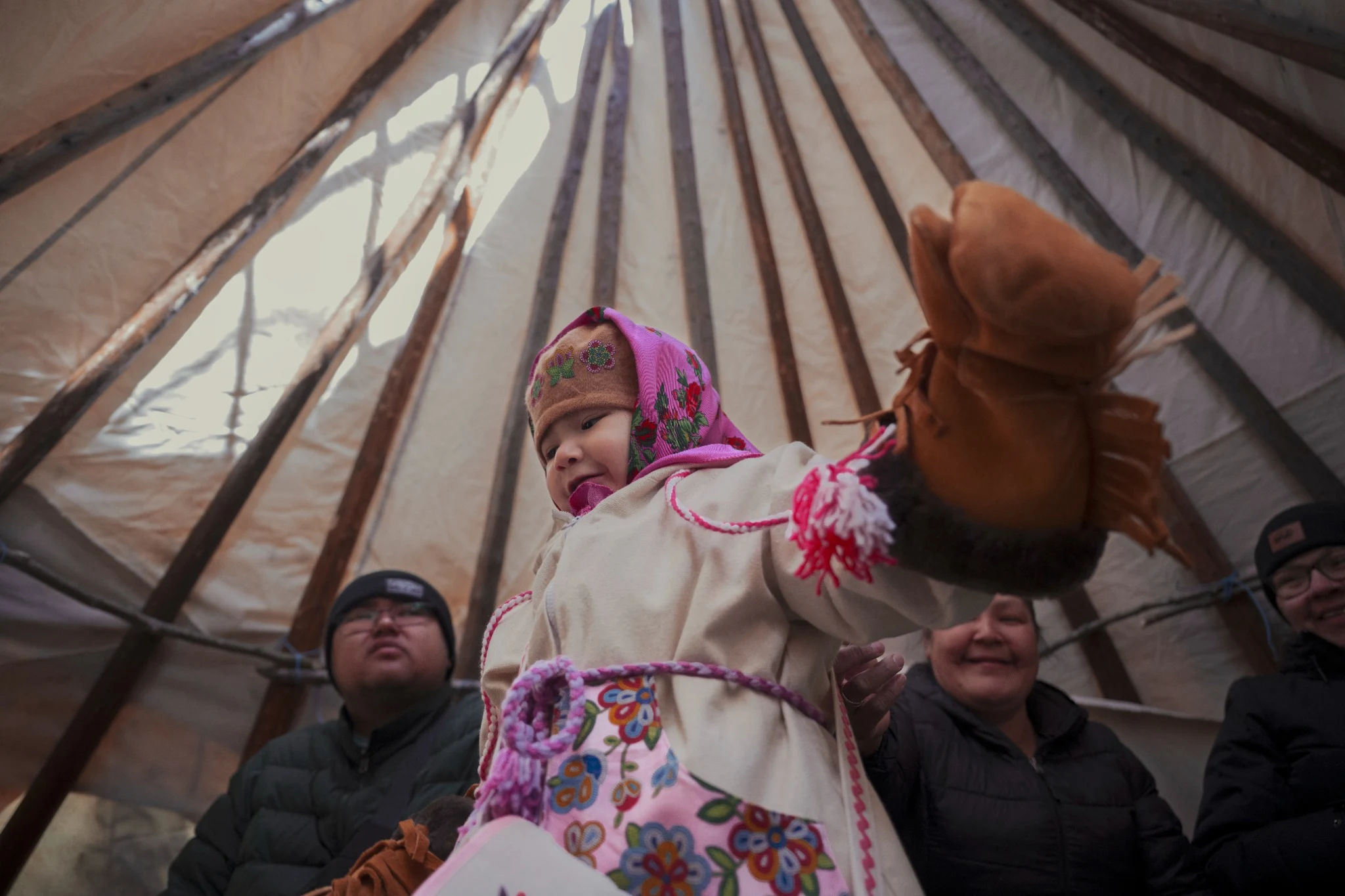 Child raising a mitten inside a tent